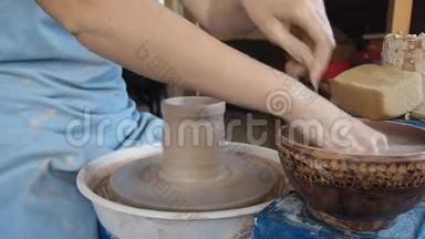 女陶工在陶工的车轮上雕刻一罐粘土。